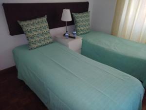 2 Betten in einem Hotelzimmer mit grüner Bettwäsche in der Unterkunft Andar com jardim e estacionamento in Paço de Arcos