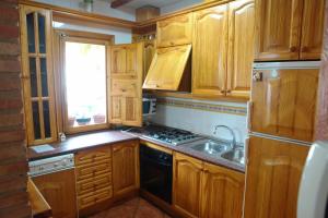 una pequeña cocina con armarios de madera y fregadero en La Buhardilla, en Arroyo Frío