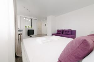 イジェフスクにあるFive Stars Studioのベッドルーム(白いベッド1台、紫色のソファ付)