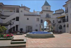 Un gran edificio con una fuente en medio de un patio. en Frente al mar, en Benalmádena