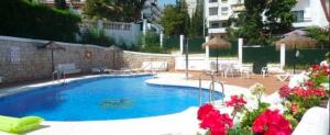 ein großer blauer Pool in einem Gebäude mit Blumen in der Unterkunft Frente al mar in Benalmádena