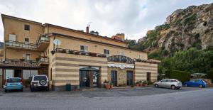 a building with cars parked in front of a mountain at Hotel Mazzurco in Cesar&ograve;