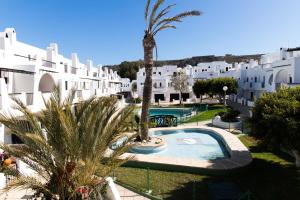 an apartment with a swimming pool and a palm tree at Casa Serene in Agua Amarga