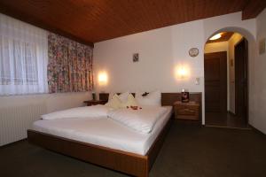- une chambre avec un grand lit blanc dans l'établissement Haus Öttl, à Ischgl