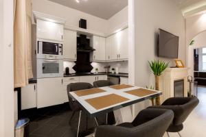 ブダペストにあるLuxury Dream Home In The Absolute Centerの白いキャビネット、テーブルと椅子付きのキッチンが備わります。