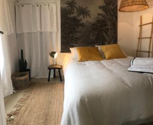 Schlafzimmer mit einem Bett mit weißer Bettwäsche und gelben Kissen in der Unterkunft Appartement Casalea - Casadibastia - Bastia centre in Bastia