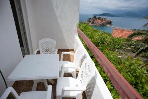 a white table and chairs on a balcony overlooking the ocean at Apartment Mina in Sveti Stefan