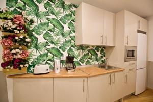 a kitchen with white cabinets and flowers on the wall at The Bridge Huertas in Madrid