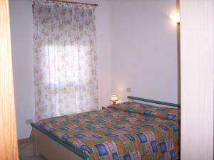 ein Schlafzimmer mit einem Bett mit einem Vorhang und einem Fenster in der Unterkunft Appartamento Federica in Valledoria