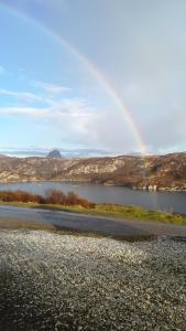 a rainbow over a body of water with a road at Achmelvich View self catering in Lochinver