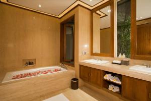 a bathroom with a tub and two sinks and a mirror at KoenoKoeni Villa in Seminyak
