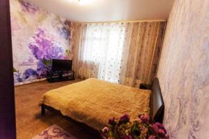 a bedroom with a bed with a yellow blanket at Apartment on Gazovikov 41 in Tyumen