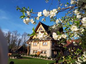 una casa con flores blancas delante de ella en Magurskie Bywanie en Witów