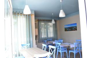 a dining room with blue chairs and tables and windows at Open Doors Bed & Breakfast in Shkodër