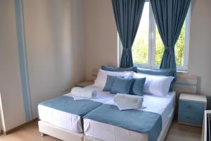 a bed with blue and white pillows and a window at Open Doors Bed & Breakfast in Shkodër
