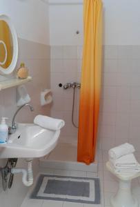 a bathroom with a shower with an orange shower curtain at Georgia's Little Village in Plataria