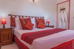 a bedroom with a large bed with orange and white pillows at Résidence Le Jardin des 4 Épices in Saint-Louis