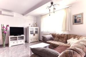 uma sala de estar com um sofá e uma televisão em Apartment Casa em Podstrana