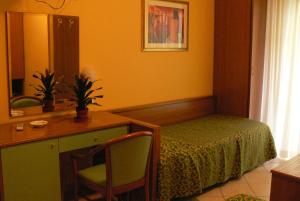 サン・ベネデット・デル・トロントにあるHotel Marioのベッド、テーブル、鏡が備わる客室です。