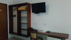 een kamer met een bureau en een televisie aan de muur bij Pousada do Tié in Ubatuba