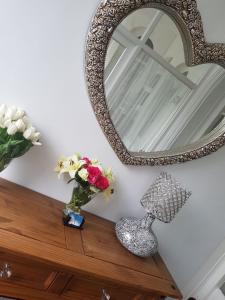 a mirror and a vase of flowers on a wooden table at Barton Hotel in Blackpool