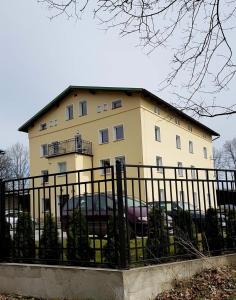 a large yellow building with a fence in front of it at Apartamenty "Kotlina" in Bystrzyca Kłodzka