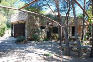 Un edificio de piedra con un banco delante. en Casa Estany, en L'Ametlla de Mar