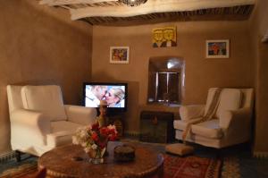 a living room with two white chairs and a tv at Kasbah Gousteau in Taroudant