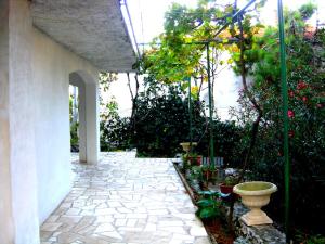 a garden with a stone walkway with a vase on it at Pansion Danijela in Rogoznica