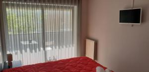 a bedroom with a bed and a window with a television at Central Bus Station Flat in Braga