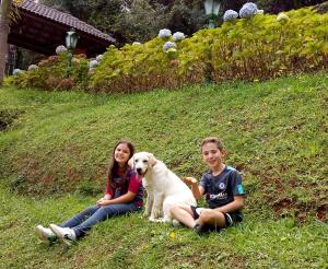 un niño y una niña y un perro sentados en una colina en Pousada Casa dos Sonhos, en Campos do Jordão