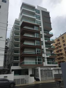 a tall building with a car parked in front of it at Cozy apartment in exclusive area Bella Vista in Santo Domingo
