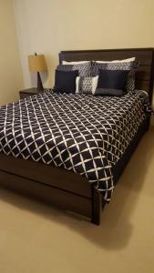 a bed with a black and white comforter and a lamp at 2 BEDROOM / 1 BATH ONLY 9 MILES TO NAVY BASE in Sinajana