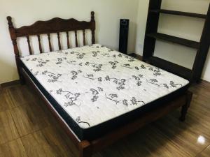 Ce lit se trouve dans un dortoir doté d'un cadre de lit en bois. dans l'établissement Rancho Vista Verde, à Ubatuba