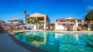 a swimming pool with chairs and umbrellas next to a house at Best Western Inn in Merced