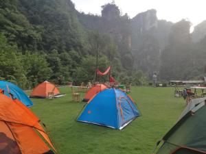 a group of tents on a field with mountains in the background at Zhangjiajie Jijiehao Inn in Zhangjiajie