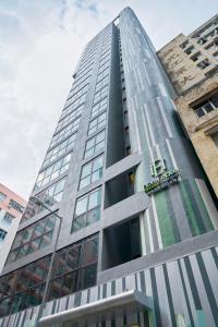 Hotel Ease Access Tsuen Wan في هونغ كونغ: مبنى زجاجي طويل وبه نوافذ على الجانب