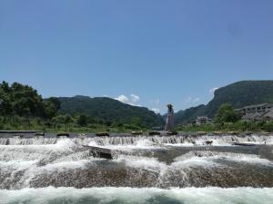 a group of waterfalls in a river with a statue at Zhangjiajie Jijiehao Inn in Zhangjiajie