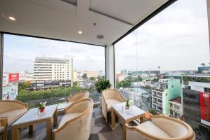 restauracja ze stołami i krzesłami oraz dużymi oknami w obiekcie Le Saigon Hotel w Ho Chi Minh