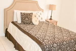 a bed with a black and white comforter and pillows at 2 BEDROOM / 1 BATH ONLY 5 MINUTES AWAY FROM BANK OF HAWAII in Sinajana