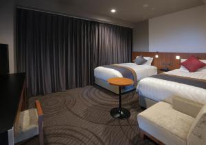 a hotel room with two beds and a chair at Kisarazu Washington Hotel in Kisarazu