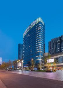 een hoog glazen gebouw in een stad 's nachts bij Mercure Yantai Golden Beach in Yantai