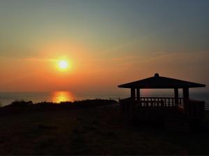 a sunset over the ocean with a gazebo at Shima Stay holoholo in Zamami