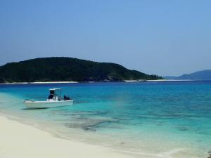 a boat in the water on a beach at Shima Stay holoholo in Zamami