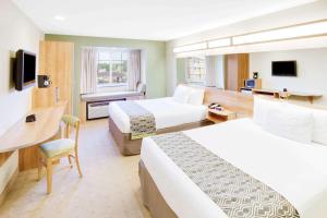 a hotel room with two beds and a desk at Microtel Inn & Suites by Wyndham Saraland in Saraland