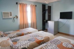 um quarto com três camas e uma televisão em Crowne Garden Hotel em Cebu