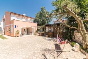 a patio of a house with a tree and a hammock at Villa Marizella in Premantura