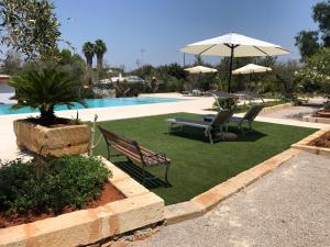 WHITE POOL Matino - Gallipoli - 7pl في ماتينو: حديقة بها كرسيين ومظلة بجوار حمام السباحة
