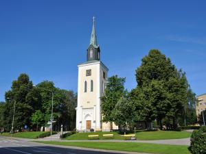 uma torre branca alta com um campanário numa rua em Hotell Linnéa em Ljungby