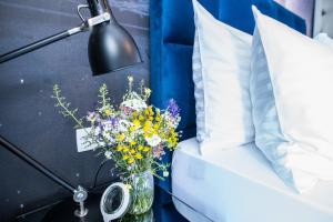 a vase of flowers next to a bed with a lamp at Olive Hill House - ground floor in Slatine +29 photos
